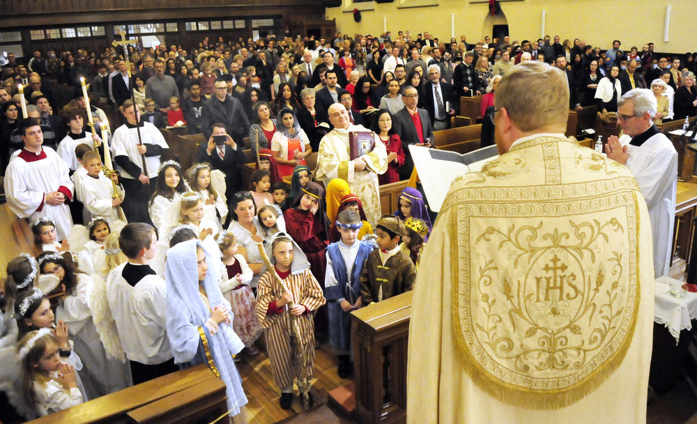 Staff Photo by Robin Rudd / The Reverend David Carter declares the birth of Jesus Christ, in front of the Nativity Scene. The youth of the parish dressed as angels, shepherds and others in a Christmas Pageant. The Vigil Mass of Christmas was celebrated at the Basilica of Saints Peter and Paul on December 24, 2021.