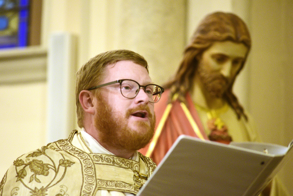 Staff Photo by Robin Rudd / The Reverend David Carter declares the birth of Jesus Christ to the packed church. The Vigil Mass of Christmas was celebrated at the Basilica of Saints Peter and Paul on December 24, 2021.