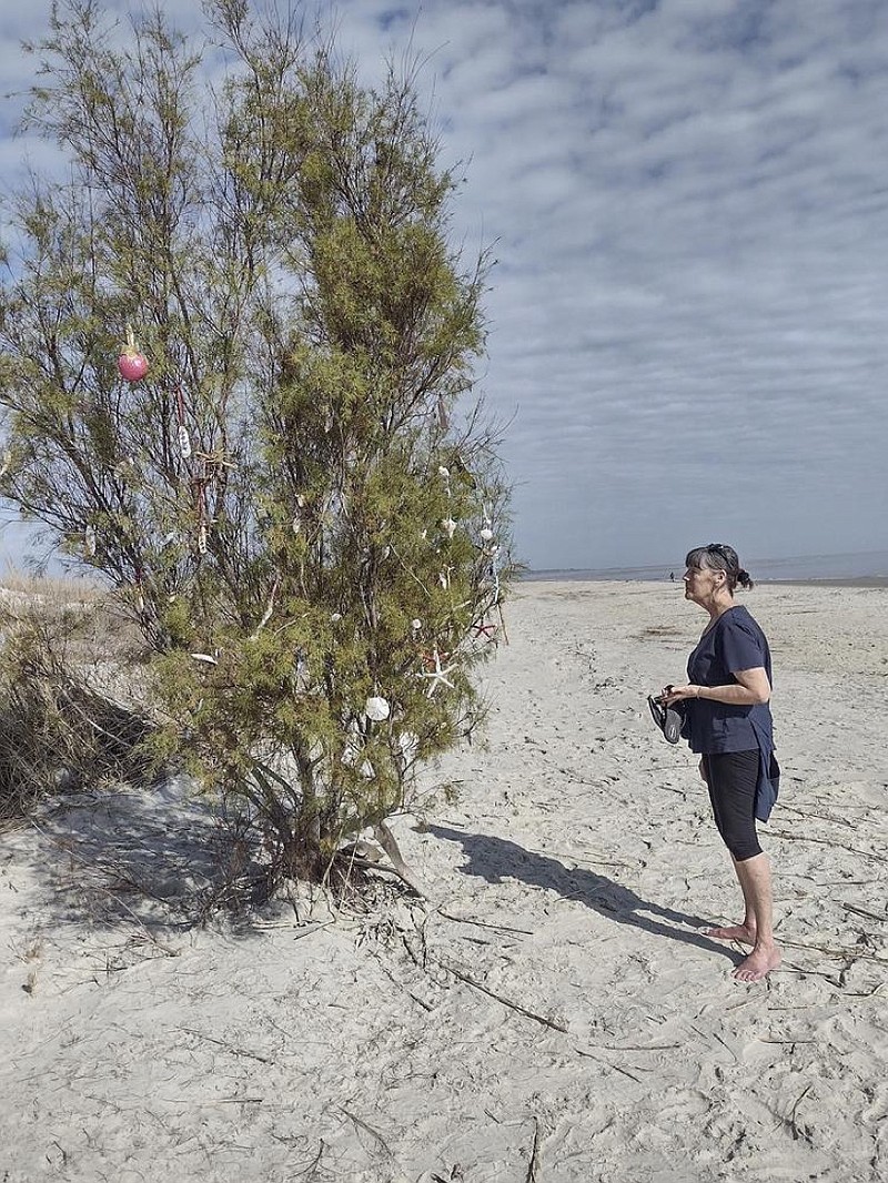 Illinois resident Nyla Wendle, who is wintering on St. Simons Island, Ga., who has sent photos of the island's impromptu beach Christmas tree back home to Peoria, much to their delight, looks over the beach Christmas tree. (Larry Hobbs/The Brunswick News via AP)

