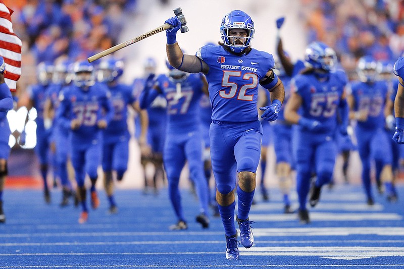 Boise State linebacker DJ Schramm (52), carrying the Dan Paul Hammer, leads Boise State onto the field before an NCAA college football game against Oklahoma State on Sept. 18, 2021, in Boise, Idaho. The Arizona Bowl was canceled on Monday night, Dec. 27, after Boise State pulled out and shut down all team activities due to COVID-19 issues within the program. (AP Photo/Steve Conner, File)