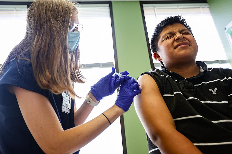 Staff photo by Troy Stolt / Joel Pedro, 13, right, winces while Nurse Practitioner Meghan Whitehead, left, administers a dose of the COVID-19 vaccine at LifeSpring Community Health on Wednesday, July 21, 2021, in Chattanooga, Tenn.