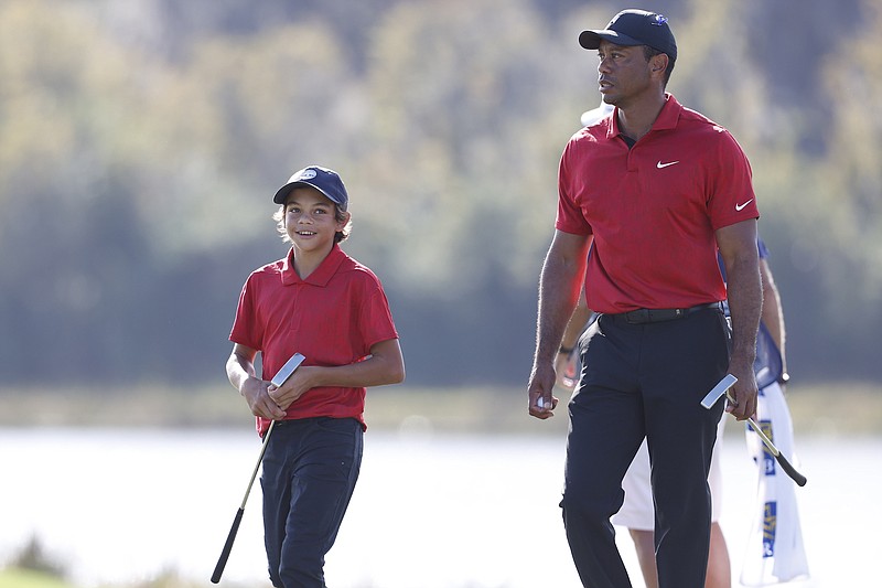 Photo by Scott Audette of The Associated Press / Tiger Woods walks off the 14th hole with son Charlie Woods during the second round of the PNC Championship golf tournament on Sunday, Dec. 19, 2021, in Orlando, Fla.