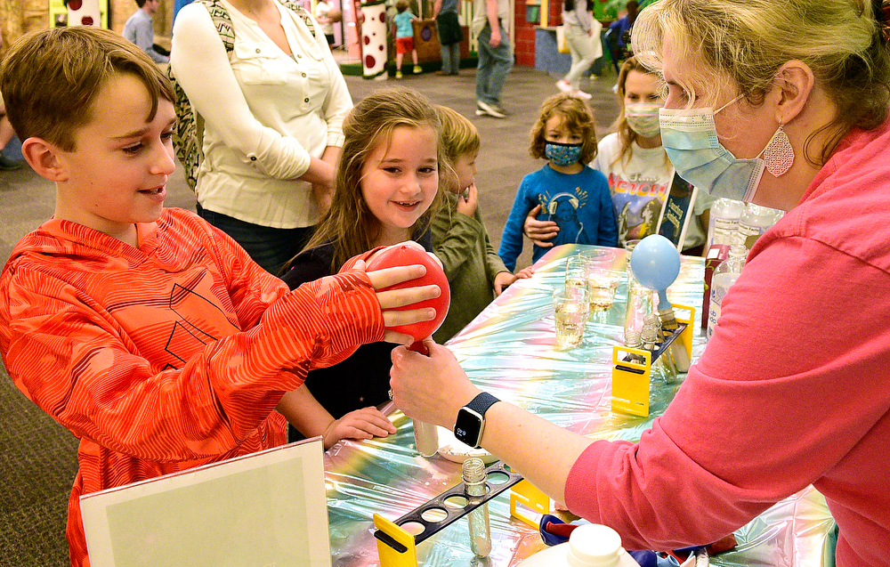 Staff Photo by Robin Rudd / From left Karson Brown does a Dancing Raisin experiment with museum staffer, Amanda Ward. Lookin on is Karson's sister Lyla. The New Year was celebrated during the 
