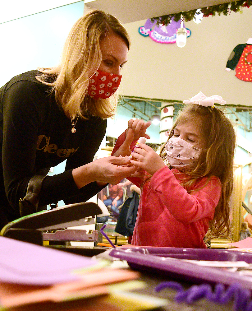 Staff Photo by Robin Rudd / Olivia Gomez, right, works with her mom, Lesley Catlett, to create a New Years hat. The New Year was celebrated during the "Cheers for the New Year" event at the Creative Discovery Museum on December 30, 2021.