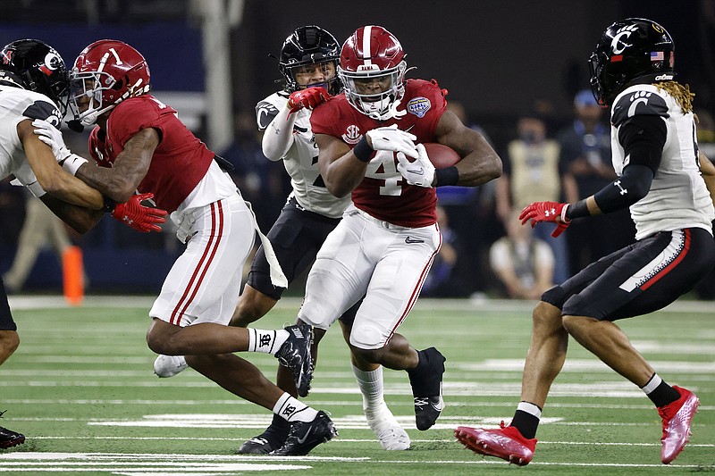 AP photo by Michael Ainsworth / Alabama running back Brian Robinson Jr. carries the ball for a first down as Cincinnati linebacker Deshawn Pace reaches from behind to tackle him during the first half of the Cotton Bowl on Friday. Robinson rushed for 204 yards to lead the top-ranked Crimson Tide to a 27-6 victory in the College Football Playoff semifinal.