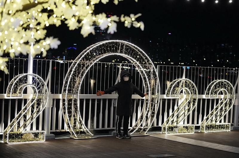 A visitor wearing a face mask poses for a photo in front of an illuminated decorations on New Year's Eve in Seoul, South Korea, Friday, Dec. 31, 2021. (AP Photo/Lee Jin-man)

