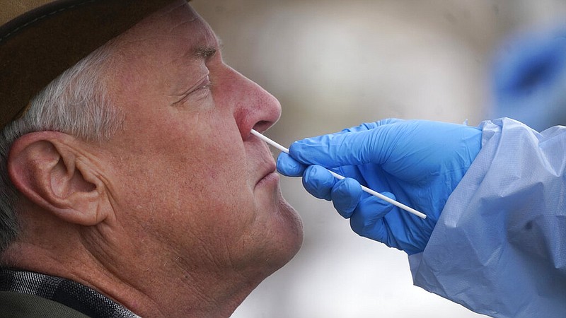 A member of the Salt Lake County Health Department COVID-19 testing staff performs a test on Gary Mackelprang outside the Salt Lake County Health Department Tuesday, Jan. 4, 2022, in Salt Lake City. (AP Photo/Rick Bowmer)