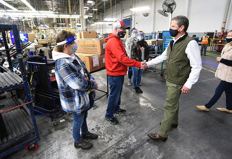 Staff Photo by Matt Hamilton / Georgia Governor Brian Kemp shakes hands with plant worker Mitch Bridges as Patricia Johnston, left, looks on at the Roper Corporation Cooking Products Plant in Lafayette, Ga. on Friday, Jan. 7, 2022. Georgia Governor Brian Kemp visited the plant after GE Appliances recently invested a $118 million expansion in Georgia.