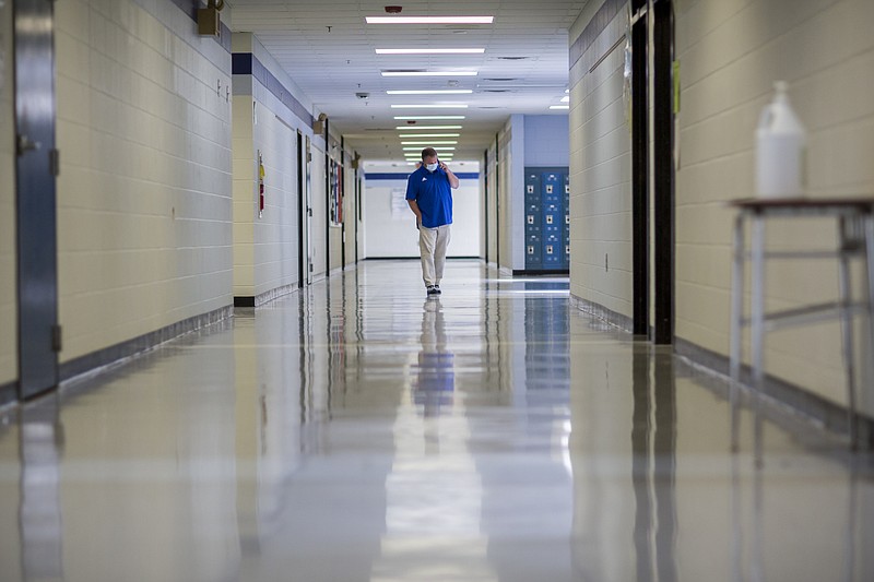 A middle school principal walks the empty halls of his school as he speaks with one of his teachers to get an update on her COVID-19 symptoms, Friday, Aug., 20, 2021, in Wrightsville, Ga. (AP Photo/Stephen B. Morton, File)