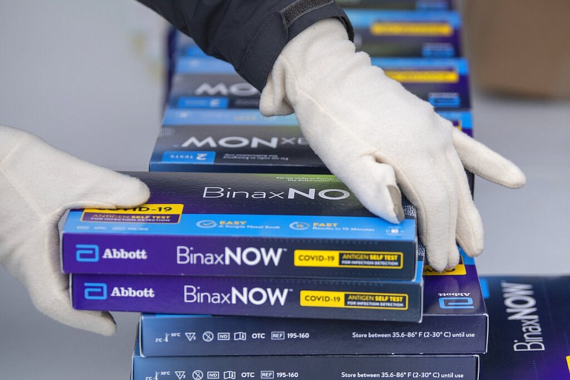 Youngstown City Health Department worker Faith Terreri grabs two at-home COVID-19 test kits to be handed out during a distribution event, Dec. 30, 2021, in Youngstown, Ohio. Starting Saturday, private health insurers will be required to cover up to eight home COVID-19 tests per month for those on their plans, the Biden administration announced Monday, as it looks to lower costs and make testing for the virus more convenient amid rising frustrations. (AP Photo/David Dermer, File)