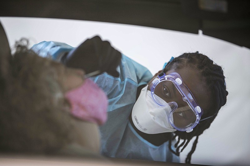 AP file photo / A nurse collects a specimen from a patient during a Georgia drive-thru COVID-19 testing site in November 2020.