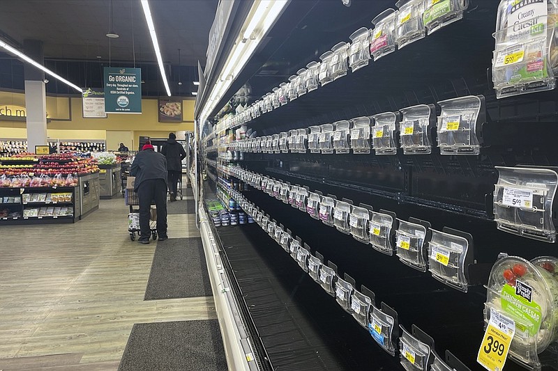 Shoppers walk past empty aisles of produce at a Safeway on Tuesday, Jan. 11, 2022, in Washington. (AP Photo/Parker Purifoy)


