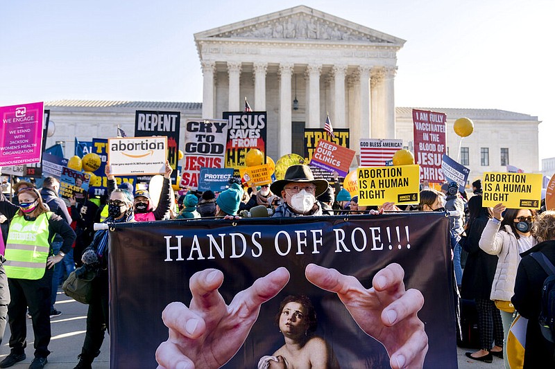 Stephen Parlato of Boulder, Colo., holds a sign that reads "Hands Off Roe!!!" as abortion rights advocates and anti-abortion protesters demonstrate in front of the U.S. Supreme Court, on Dec. 1, 2021, in Washington. With Roe v. Wade facing its strongest threat in decades, a new poll finds Democrats increasingly view protecting abortion rights as a high priority for the government.(AP Photo/Andrew Harnik, File)