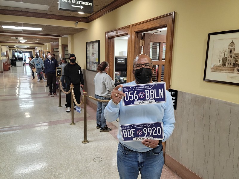 Photo by Logan Hullinger / Joe Vesselles, assistant manager at the Hamilton County Clerk's Office, shows off the state's new license plates Friday in front of a long line of residents waiting to renew their tags.