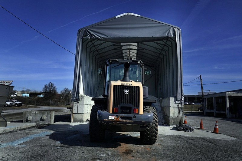 A tractor sits in front of a pile of salt used to create a brine that will help clear road of ice and snow ahead of a winter storm at the GDOT's Maintenance Activities Unit location on Friday, Jan. 14, 2022, in Forest Park, Ga. (AP Photo/Brynn Anderson)


