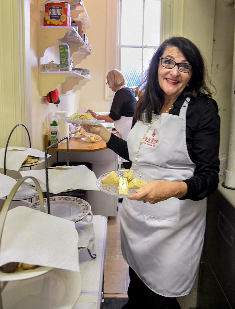 Photo by Mark Gilliland / Cynthia Pennington carries a plate of finger sandwiches.