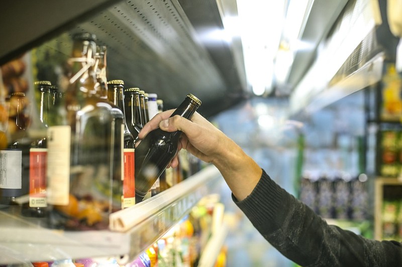 Unrecognizable man buying beer in a supermarket store. beer alcohol tile / Getty Images
