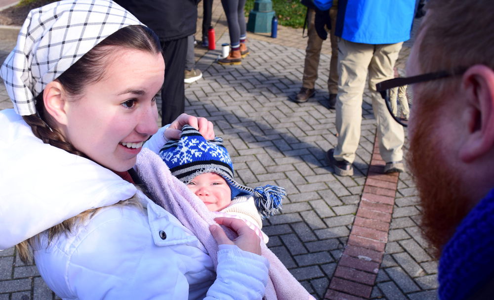 Staff Photo by Robin Rudd / Anders Olson, held by his godmother Hannah Westerman, gives the Rev. David Carter a smile during Saturday's rally.