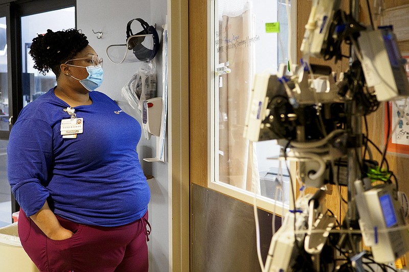 Staff photo by C.B. Schmelter / Patient Care Technician Nastassia Hinton checks on a patient inside the COVID-19 intensive care unit at Erlanger on Monday, Feb. 22, 2021 in Chattanooga.