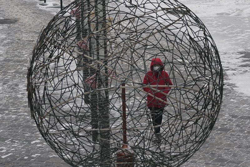 A woman wearing a mask to protect from the coronavirus walks past a globe shaped wire sculpture in Beijing, China, Saturday, Jan. 22, 2022. (AP Photo/Ng Han Guan)


