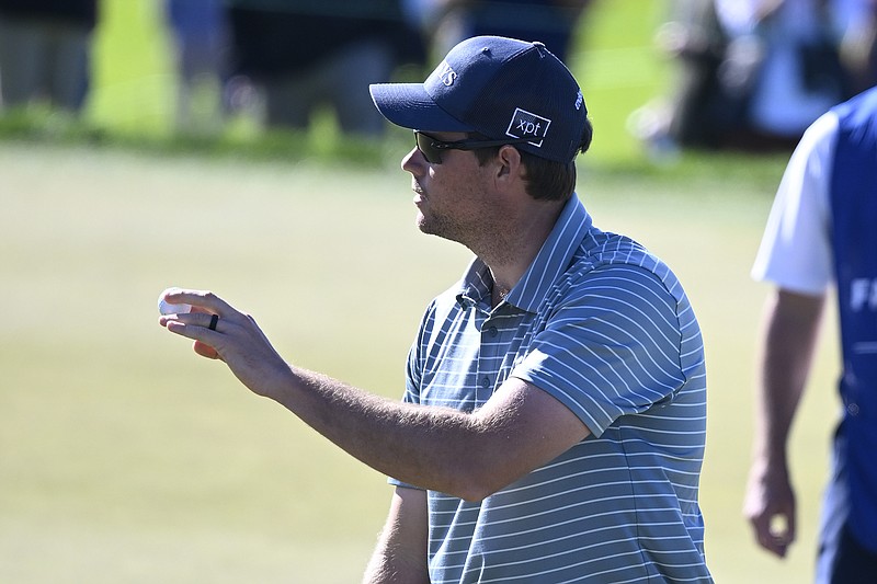 AP photo by Denis Poroy / Adam Schenk holds up his golf ball after finishing his round on Torrey Pines' North Course at the Farmers Insurance Open on Thursday in San Diego. Schenk shot a 62 and shared the lead with Jon Rahm and Justin Thomas.