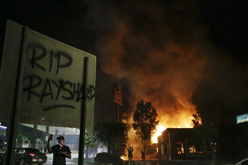 File-In this Saturday, June 13, 2020 file photo, "RIP Rayshard" is spray-painted on a sign as flames engulf a Wendy's restaurant where Rayshard Brooks was shot and killed by police in Atlanta. (AP Photo/Brynn Anderson, File)


