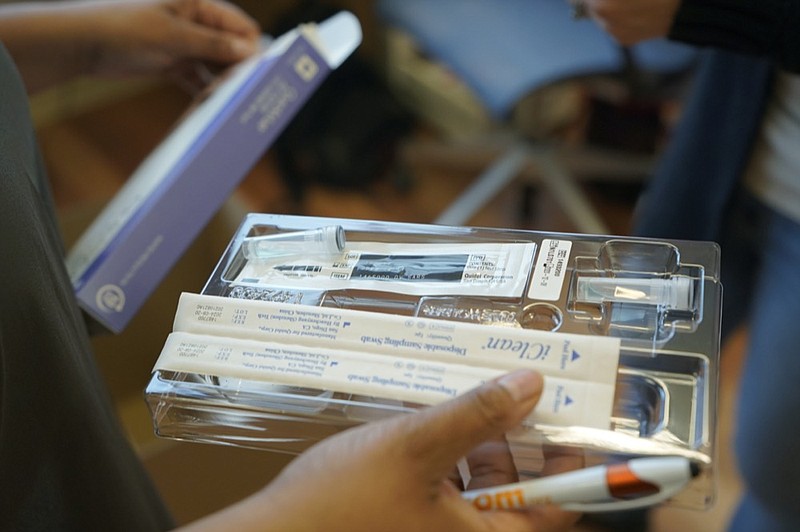 Kristin Travis, a community outreach doula, holds a home COVID-19 test kit Thursday, Feb. 3, 2022, while picking up supplies at Open Arms Perinatal Services before going out to visit some of her clients in Seattle. (AP Photo/Ted S. Warren)


