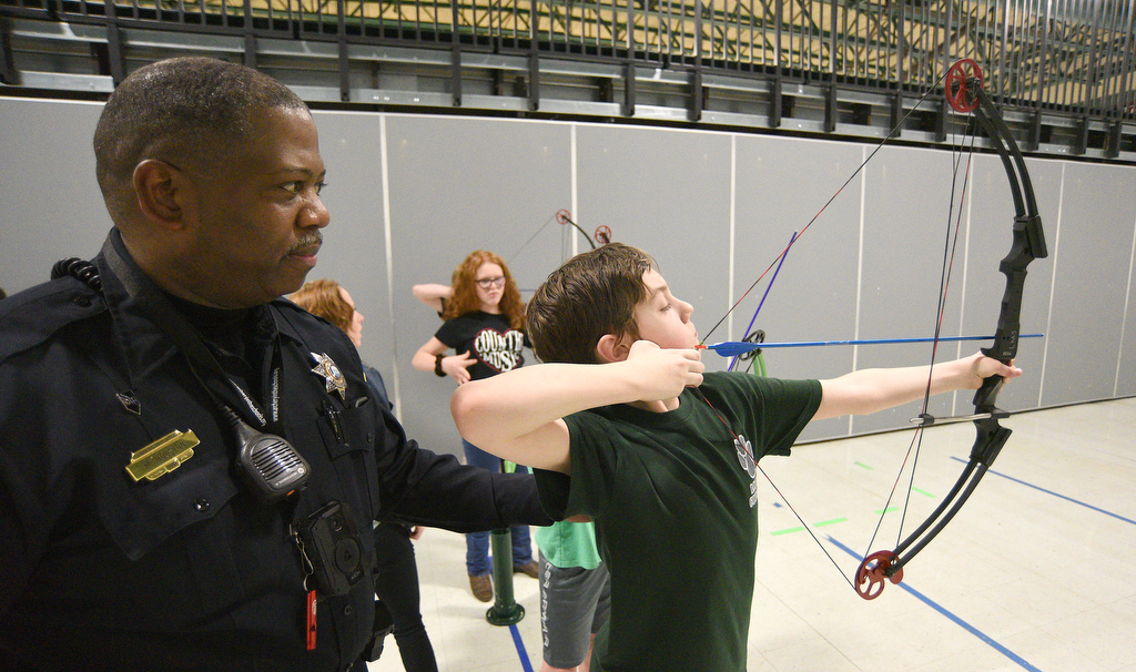 Staff Photo by Matt Hamilton / School resource officer Mike Houston watches as Logan Mabry, 11, aims an arrow during archery practice at Lofts Middle School in Hixson on Thursday, February 17, 2022.