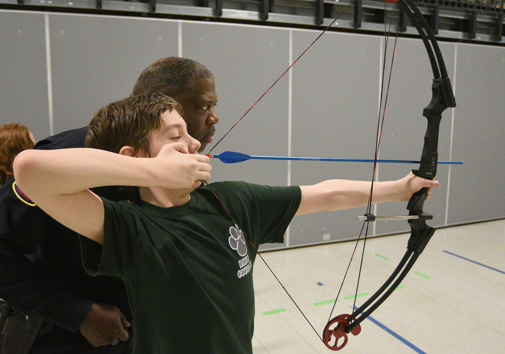 Staff Photo by Matt Hamilton / School resource officer Mike Houston watches as Logan Mabry, 11, aims an arrow during archery practice at Lofts Middle School in Hixson on Thursday, February 17, 2022.