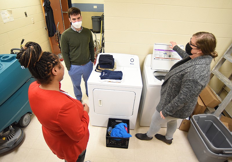 Staff Photo by Matt Hamilton / School counselors Dhyana Hodge, left, and James Moore talk with Community Forward School Coordinator Bailey Gibson about the new washer and dryer at Orchard Knob Elementary School on Wednesday, Feb. 16, 2022.