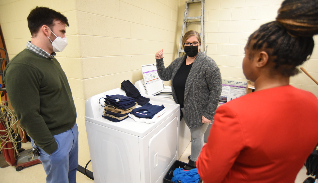 Staff Photo by Matt Hamilton / School counselors Dhyana Hodge, right, and James Moore talk with Community Forward School Coordinator Bailey Gibson, middle, about the new washer and dryer at Orchard Knob Elementary School on Wednesday, Feb. 16, 2022.