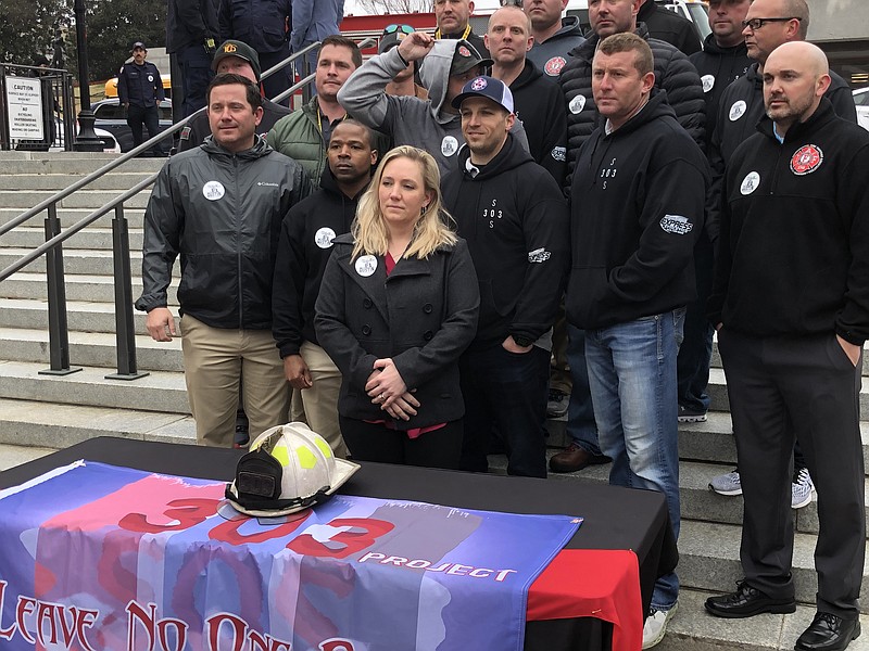 Firefighters from Cleveland, Tenn., and across the state stand with Jennifer Samples, a Cleveland police officer, on Wednesday as they advocate for the James "Dustin" Samples Act, which requires Tennessee firefighters' post-traumatic stress disorder problems be covered under state workers' compensation laws. Sample's husband, Cleveland Fire Department Capt. James "Dustin" Samples, took his life in 2020 following a years-long struggle with PTSD. (Staff photo by Andy Sher)