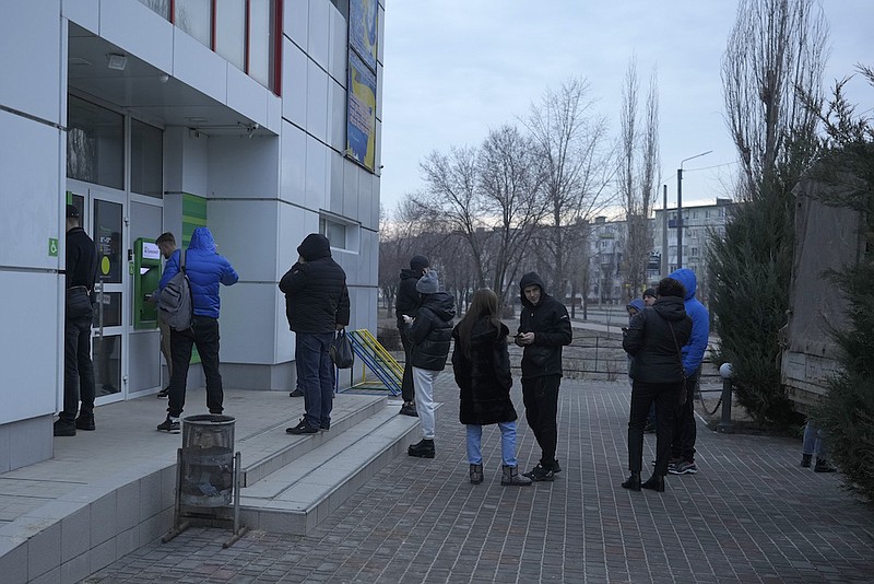 People queue to use an ATM machine outside in Sievierodonetsk, the Luhansk region, eastern Ukraine, Thursday, Feb. 24, 2022. Russian President Vladimir Putin on Thursday announced a military operation in Ukraine and warned other countries that any attempt to interfere with the Russian action would lead to "consequences you have never seen." (AP Photo/Vadim Ghirda)