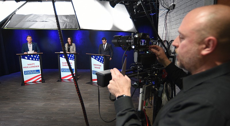 Staff Photo by Matt Hamilton / SociallyU Studio CEO Andre Dantzler, right, adjusts a camera as the candidates, from left, Matt Hullander, Sabrena Smedley and Weston Wamp stand behind their podiums before the start of the Hamilton County Mayoral Republican Primary Debate on Monday, February 21, 2022 at SociallyU Studio.