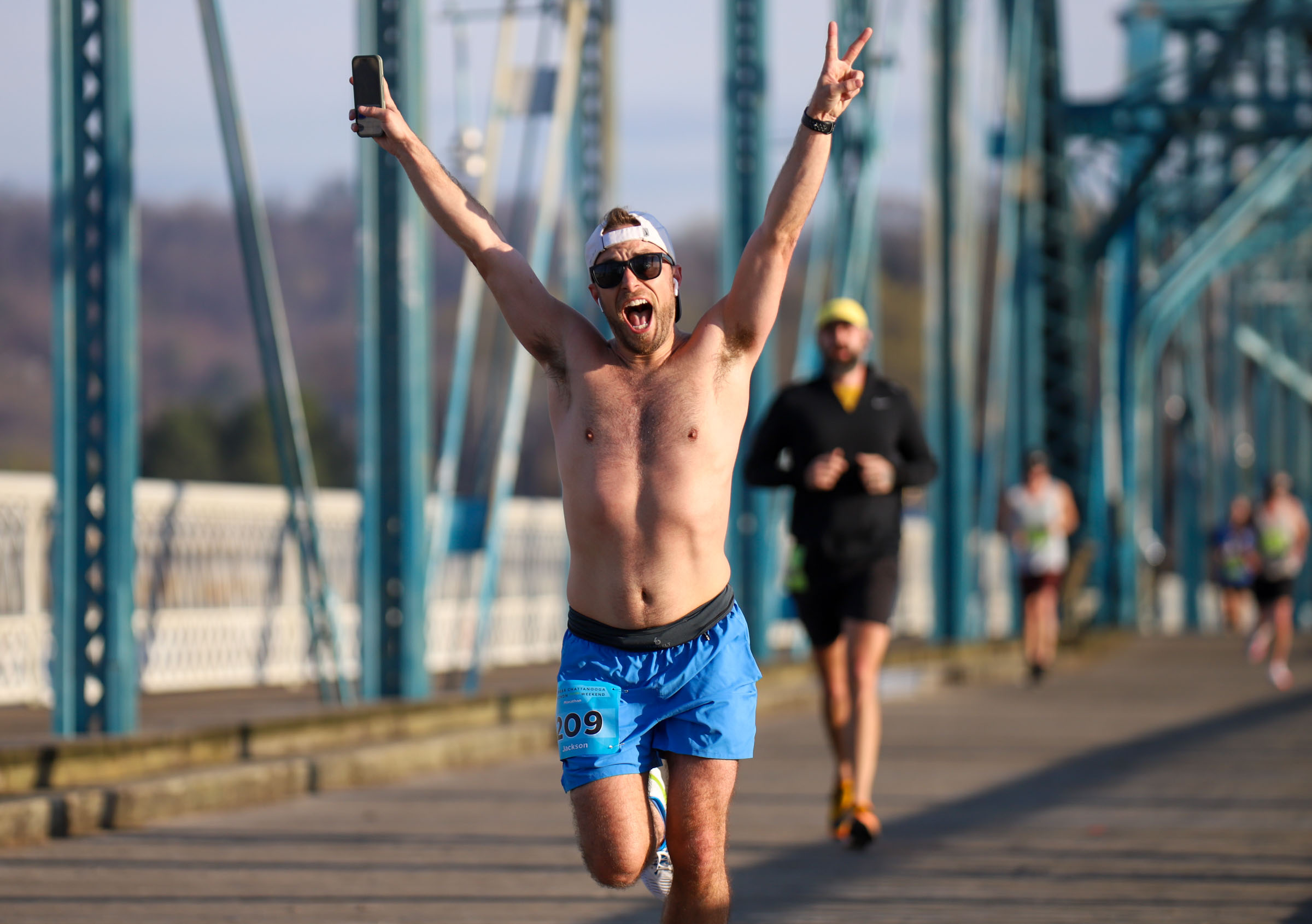 Staff Photo by Olivia Ross / Jackson Stout raises peace signs as he runs across the Walnut Street Bridge on March 6, 2022. The Erlanger Chattanooga Marathon is a full weekend complete with a marathon, half marathon, relays, 5k, and kid's fun run.