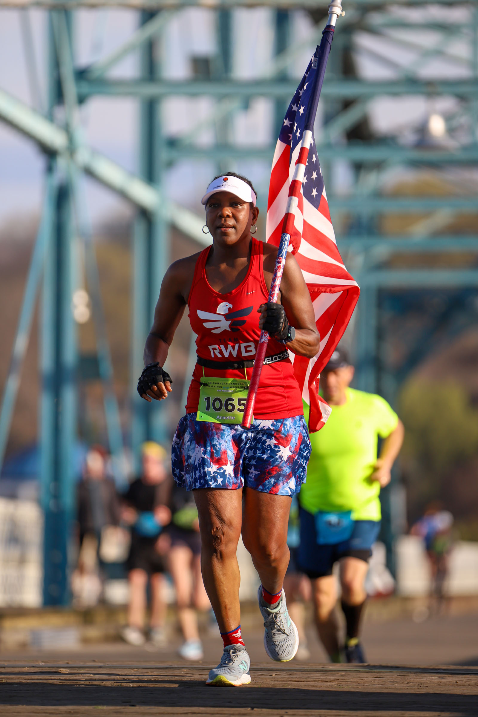 Staff Photo by Olivia Ross / Annette Tolliver carries an American flag as she runs across the Walnut Street Bridge on March 6, 2022. The Erlanger Chattanooga Marathon is a full weekend complete with a marathon, half marathon, relays, 5k, and kid's fun run.