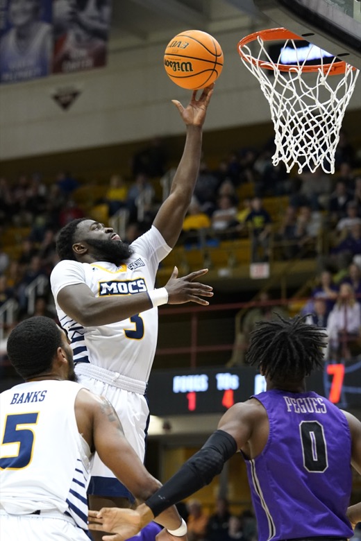 Chattanooga guard David Jean-Baptiste (3) shoots as Chattanooga forward Darius Banks (5) and Furman guard JP Pegues (0) look for the rebound in the first half of an NCAA college basketball championship game for the Southern Conference tournament, Monday, March 7, 2022, in Asheville, N.C. (AP Photo/Kathy Kmonicek)
