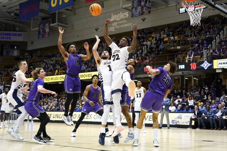 Furman guard Alex Hunter (10) and Chattanooga forwards KC Hankton (1) and Silvio De Sousa (22) leap for a loose ball in the first half of an NCAA college basketball championship game for the Southern Conference tournament, Monday, March 7, 2022, in Asheville, N.C. (AP Photo/Kathy Kmonicek)