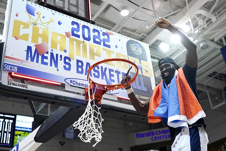 Chattanooga guard David Jean-Baptiste waves a piece of the basketball net to celebrate his team's win over Furman in an NCAA college basketball championship game for the Southern Conference tournament, Monday, March 7, 2022, in Asheville, N.C. (AP Photo/Kathy Kmonicek)