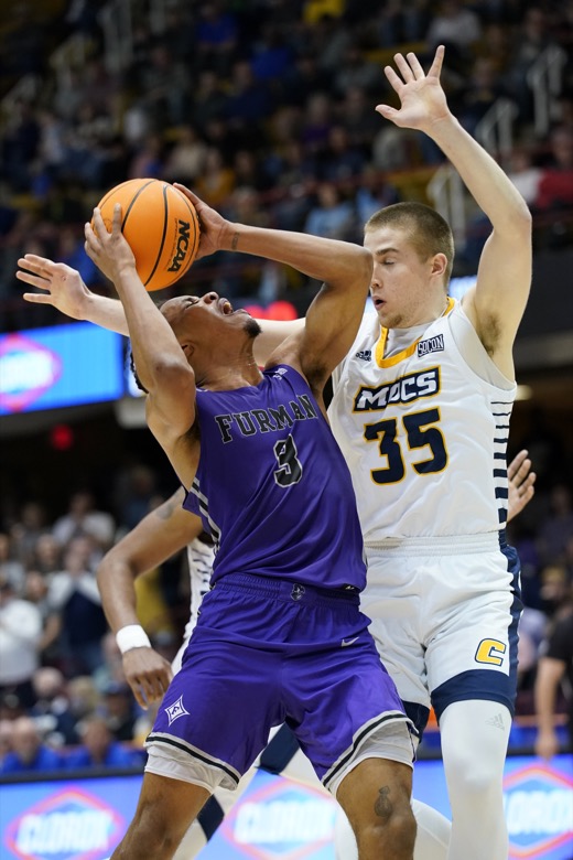 Furman guard Mike Bothwell (3) tries to shoot around Chattanooga guard Grant Ledford (35) in the second half of an NCAA college basketball championship game for the Southern Conference tournament, Monday, March 7, 2022, in Asheville, N.C. (AP Photo/Kathy Kmonicek)