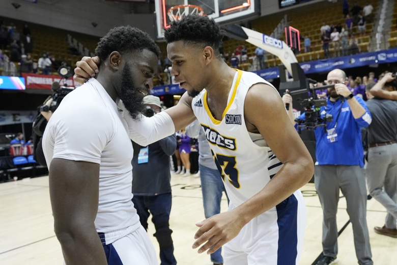 Chattanooga guard David Jean-Baptiste, left, is congratulated by center Avery Diggs (23) after making the winning basket to defeat Furman in an NCAA college basketball championship game for the Southern Conference tournament, Monday, March 7, 2022, in Asheville, N.C. (AP Photo/Kathy Kmonicek)