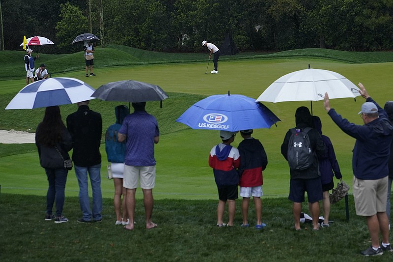 AP photo by Lynne Sladky / Golf fans watch Xander Schauffele putt on the ninth hole at TPC Sawgrass during a rainy first round at The Players Championship on Friday in Ponte Vedra Beach, Fla.