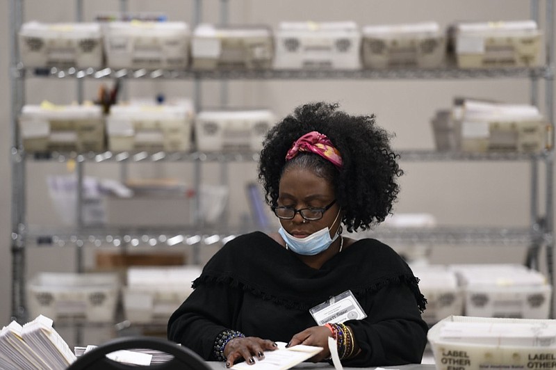 FILE - A Cobb County election official handles ballots during an election audit, on Nov. 16, 2020, in Marietta, Ga. (AP Photo/Mike Stewart, File


