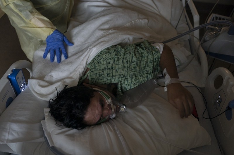 FILE - Registered nurse Nvard Termendzhyan helps Julio Valladares, 46, change his position while treating him in a COVID-19 unit at Providence Holy Cross Medical Center in Los Angeles, Dec. 13, 2021. (AP Photo/Jae C. Hong, File)


