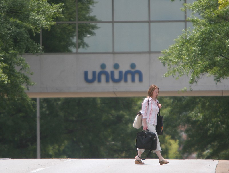 Staff File Photo / A woman walks across Walnut Street in front of Unum's offices in downtown Chattanooga.