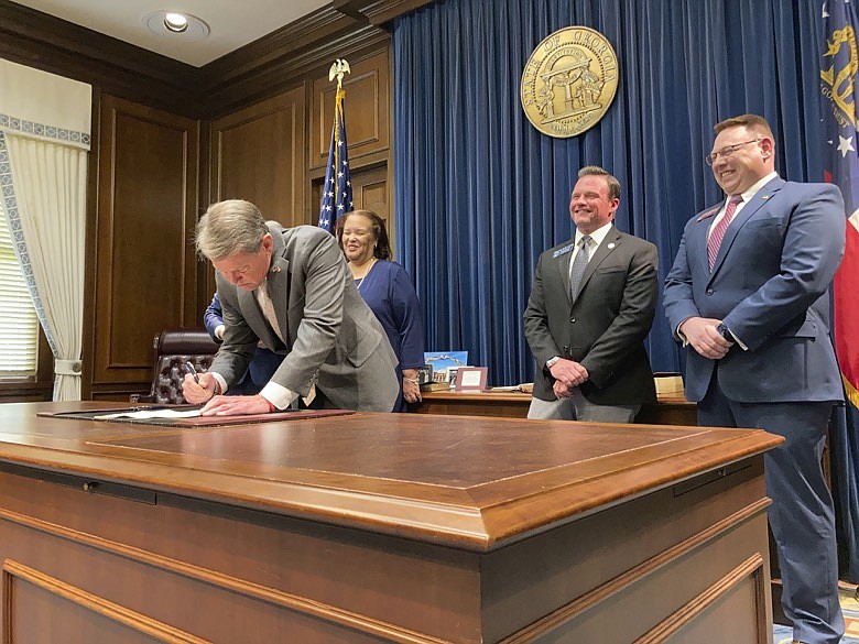 Georgia Gov. Brian Kemp signs a bill to give state income refunds of more than $1.1 billion on Wednesday, March 23, 2022, at the Georgia capitol in Atlanta. The measure gives refunds of $250 to $500 to people who filed tax returns for 2020 and 2021. (AP Photo/Jeff Amy)