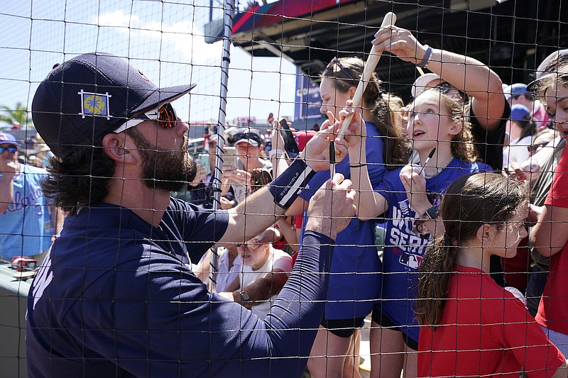 AP photo by Steve Helber / Atlanta Braves shortstop Dansby Swanson hands a souvenir back to a fan as he signs autographs before a spring training game against the visiting Toronto Blue Jays on Monday at CoolToday Park in North Port, Fla.
