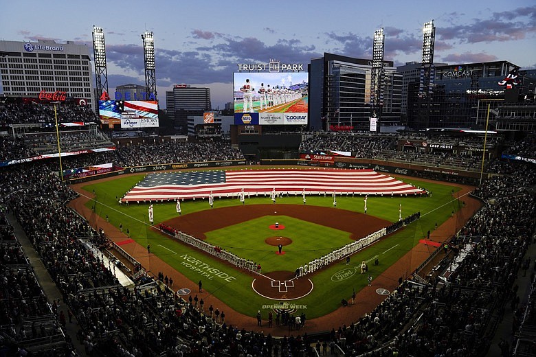 AP photo by Brynn Anderson / The Atlanta Braves and Cincinnati Reds line up during the national anthem before their season opener Thursday night at Truist Park in Atlanta.