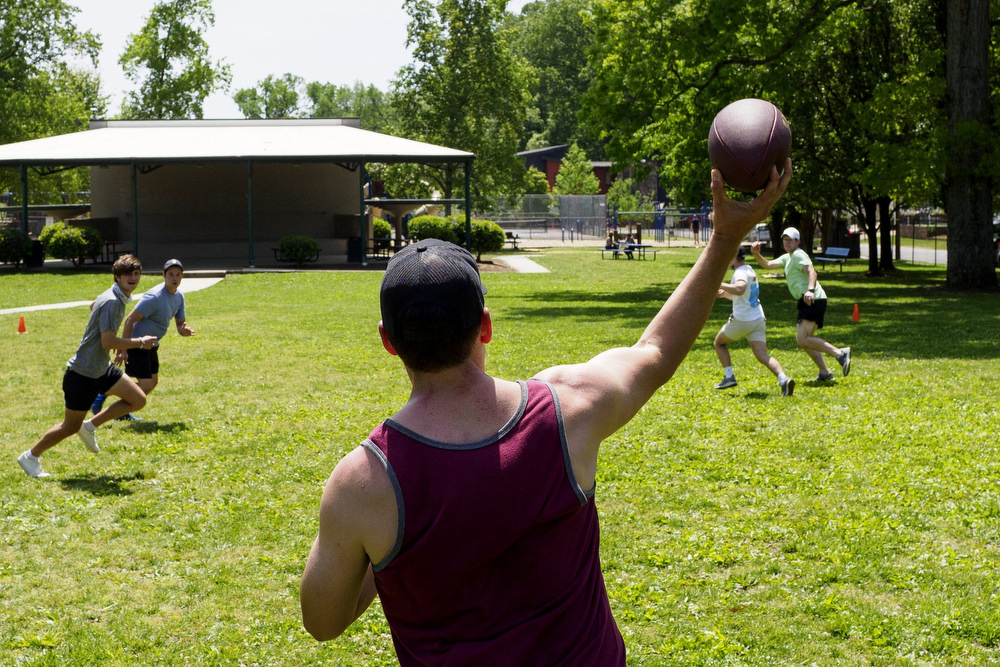 Staff photo by C.B. Schmelter / Taylor White, center, throws a pass while tossing around a football with his coworkers on their day off at Riverview Park on Monday, April 26, 2021 in Chattanooga, Tenn.