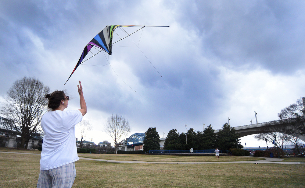 Staff Photo by Matt Hamilton / Chattanooga resident Rebecca Holder helps launch a two-handed kite as her husband Andy controls the kite on Saturday, January 1, 2022 in Coolidge Park as a storm blows in. Winds gusted above 30 m.p.h. as he got the kite up into the sky above the park.